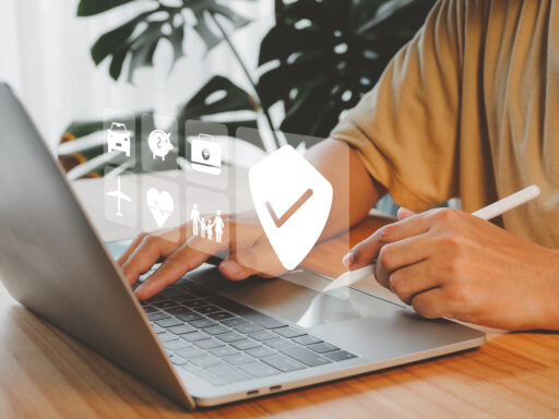 Person arbeitet an einem Laptop mit digitalen Symbolen für Versicherungen und Finanzen, darunter ein großes Häkchen-Symbol im Vordergrund.