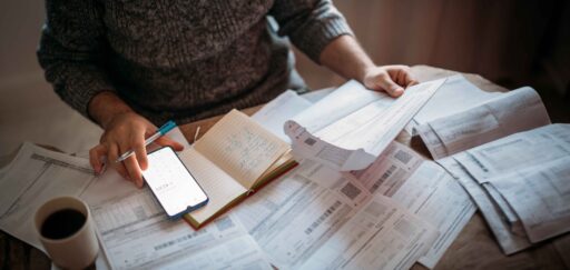 viele gehaltsabrechnungen liegen vor einer person mit einem taschenrechner auf dem tisch