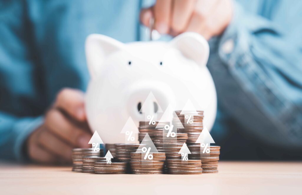 Symbolisches Sparschwein vor einer Person und im Vordergrund stehen Geldmünzen gestalpelt