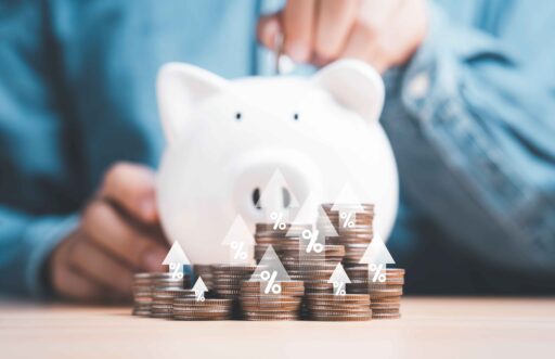 Symbolisches Sparschwein vor einer Person und im Vordergrund stehen Geldmünzen gestalpelt